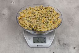 21.46 ounces of ground products from garbage disposal, displayed on digital scale, placed on granite-looking table. Mess of assorted scraps, including fibers, bones, etc.