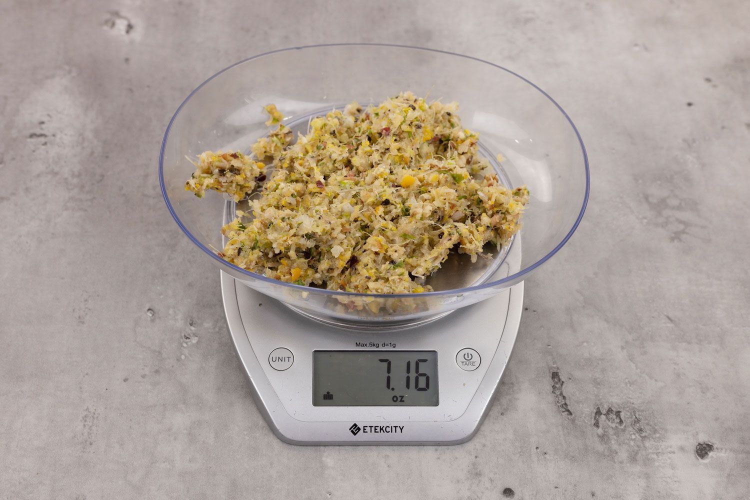 7.16 ounces of ground products from garbage disposal, displayed on digital scale, placed on granite-looking table. Mess of assorted scraps, including dietary fibers, shredded bones, etc.