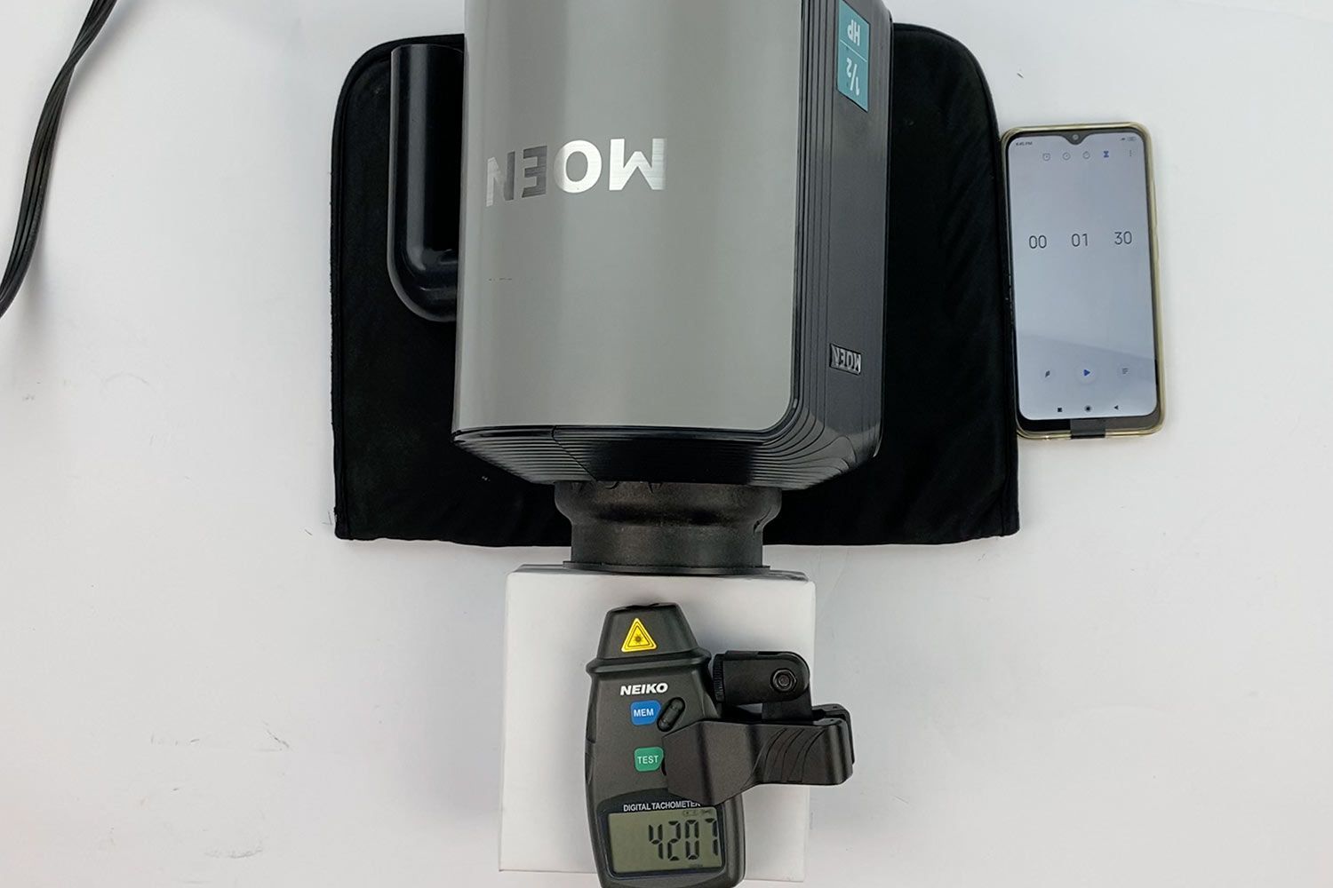 A digital tachometer is measuring the speed of the motor/flywheel of the Moen 1/2-HP garbage disposal in our speed test. A smartphone is running the timer app.