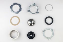 Parts of 3-Bolt Mount assembly on white platform, including backup flange, mounting ring, snap ring, fiber gasket, stopper, cushion mount, sink flange with “Moen” engravings, removable sink baffle, lower mounting ring.