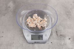 1.84 ounces of ground fish scraps from garbage disposal, displayed on digital scale, placed on granite-looking table. Mess of assorted shredded bones and raw fibrous tissue. 