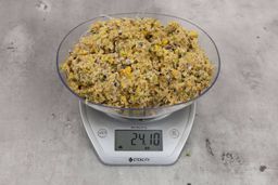 24.1 ounces of ground assorted scraps, including dietary fibers, bones, etc., on digital scale, on granite-looking top.