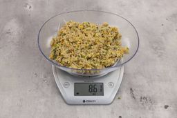 8.61 ounces of visible fish pin bones in mess of ground assorted scraps, on digital scale, on granite-looking top.