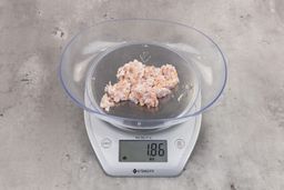 1.86 ounces of ground chicken scraps from garbage disposal, displayed on digital scale, placed on granite-looking table. Mess of shredded tissues and shredded bones.