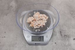 1.97 ounces of ground fish scraps from garbage disposal, displayed on digital scale, placed on granite-looking table. Mess of assorted shredded bones and raw fibrous tissue.