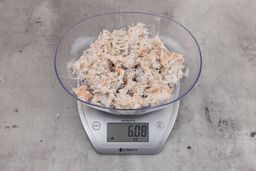 6.08 ounces of ground fish scraps from garbage disposal, displayed on digital scale, placed on granite-looking table. Pin bones among a mess of raw fibrous tissue.