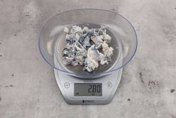 2.8 ounces of fish vertebrae among mess of shredded fish skin, on digital scale, on granite-looking top.