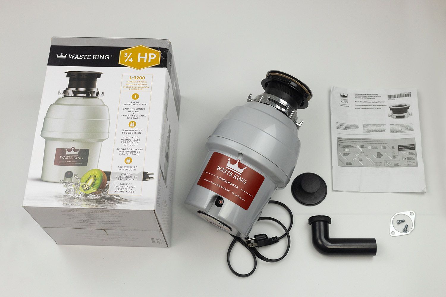 Waste King L3200 3/4 HP Garbage Disposal, EZ Mount on top, its box, user manual, stopper, elbow tube, rubber gasket, flange, and bolts.