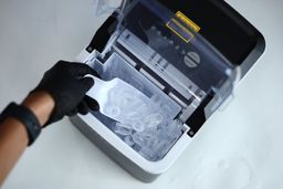 Ice being scooped out of an ice basket inside a portable ice maker.