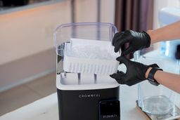 A full basket of ice being removed from a countertop portable ice maker.