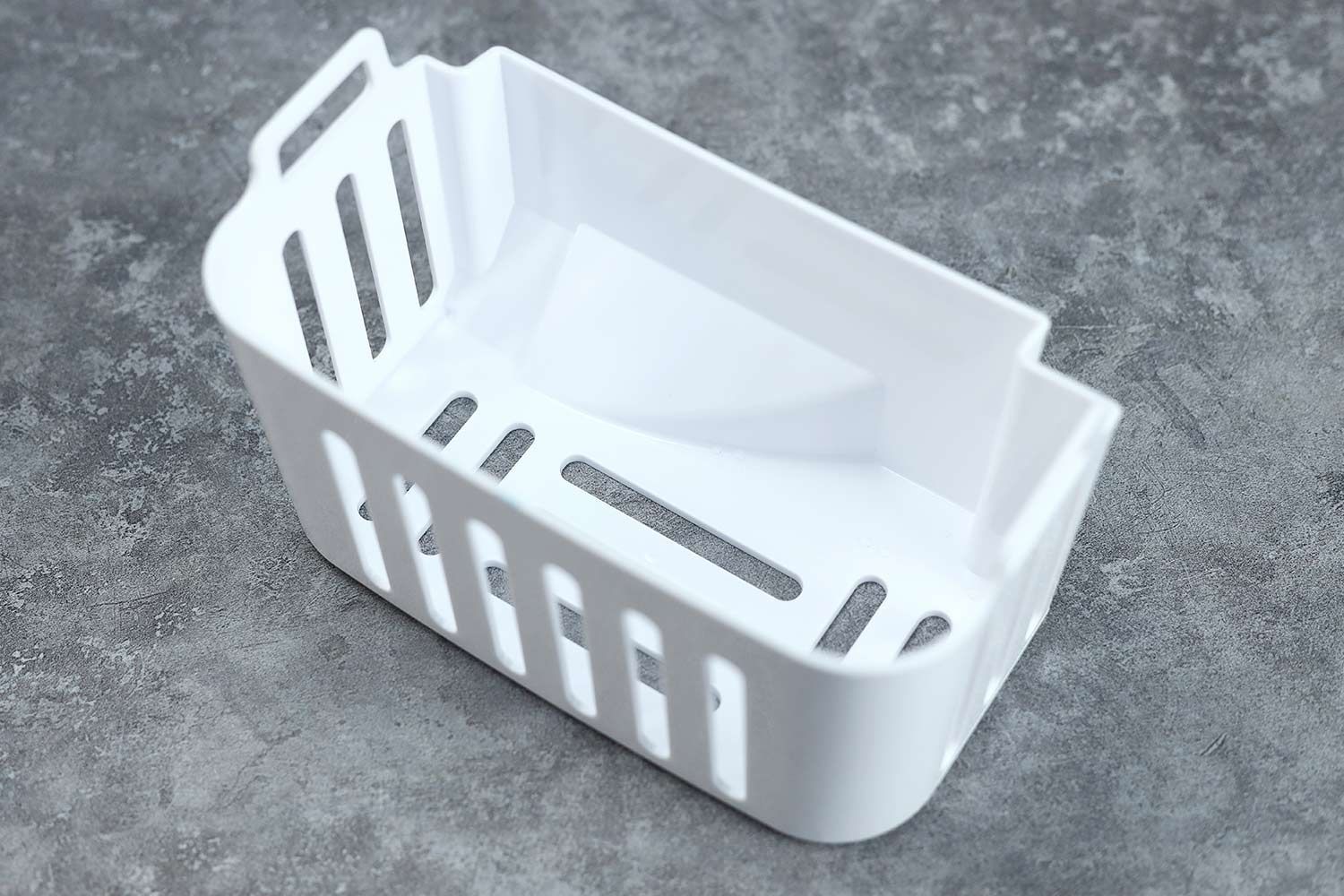 A close up of an ice basket from a countertop ice making machine against a gray marble-like background.