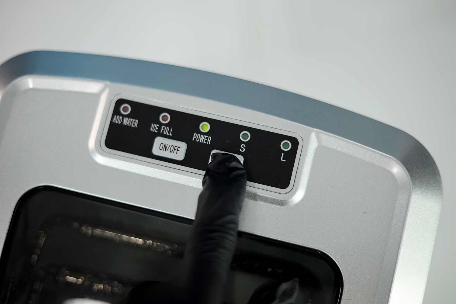 Alt: The Select button being pressed on a countertop ice maker to choose the ice size.