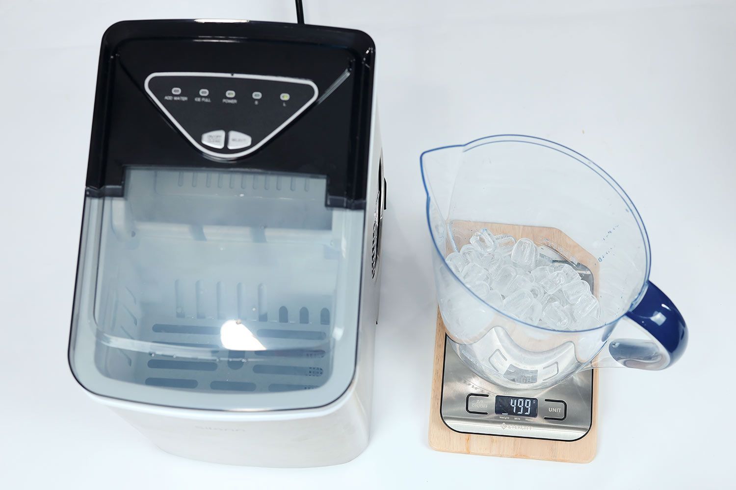 One full basket of ice from a portable ice maker being measured in a jug on a scale recording a total of 499 grams of ice.