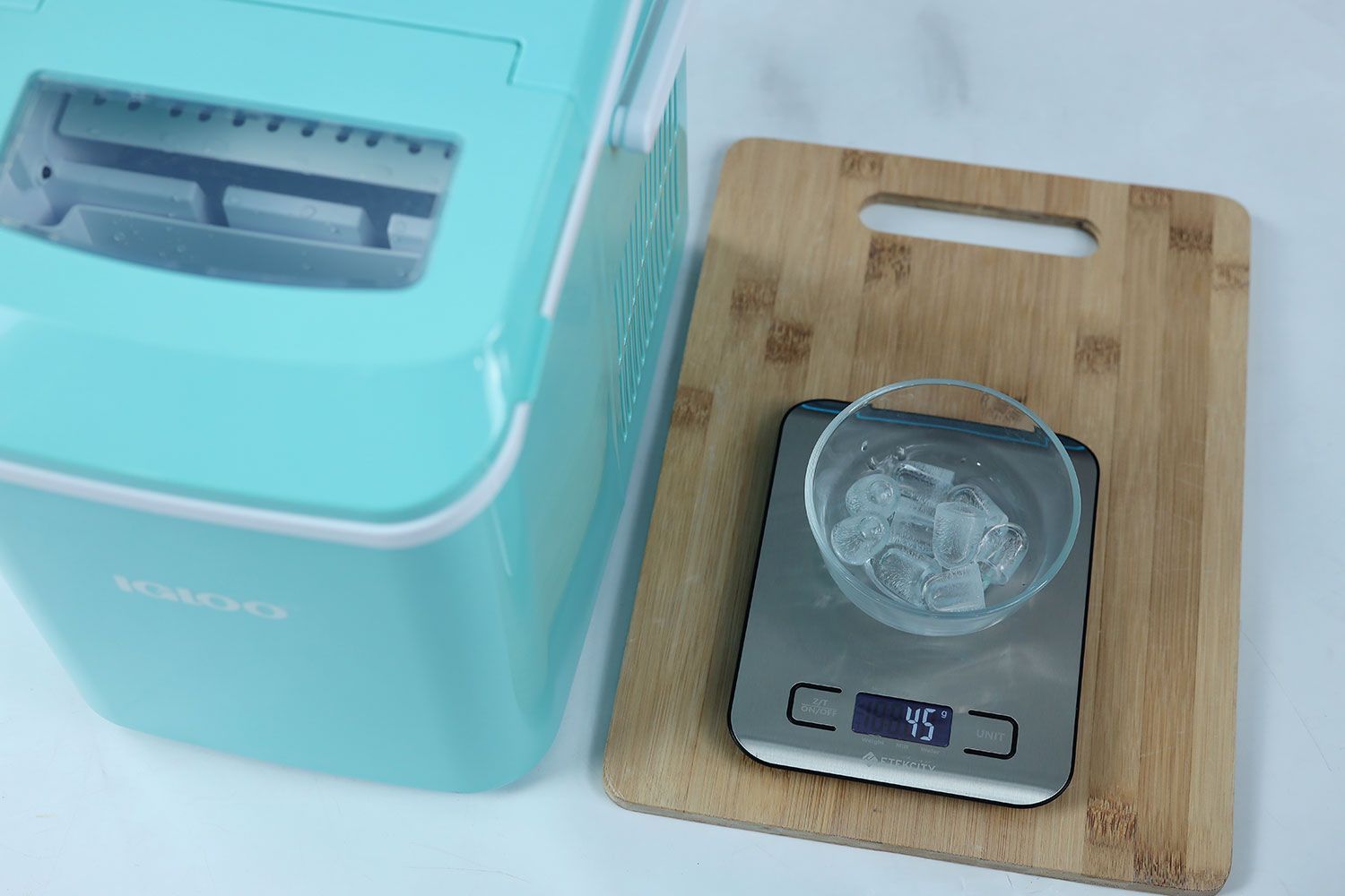 Nine ice bullets in a small bowl on a scale weight 45 grams pictured next to a countertop ice maker. 