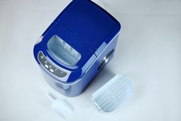 A top down view of an ice basket and ice scoop resting next to a portable countertop ice maker.