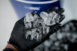 A close up view of a hand holding ice left overnight in a portable ice maker.