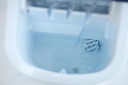 A close up of water inside the reservoir of a portable countertop ice machine.