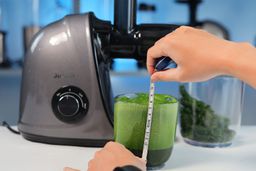 container of kale juice next to Jocuu juicer