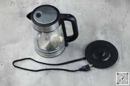 On the right is the carafe of the Amazon Basics Electric Glass and Steel Kettle (F-625C). On the left is its power base with its power cord extended from below.