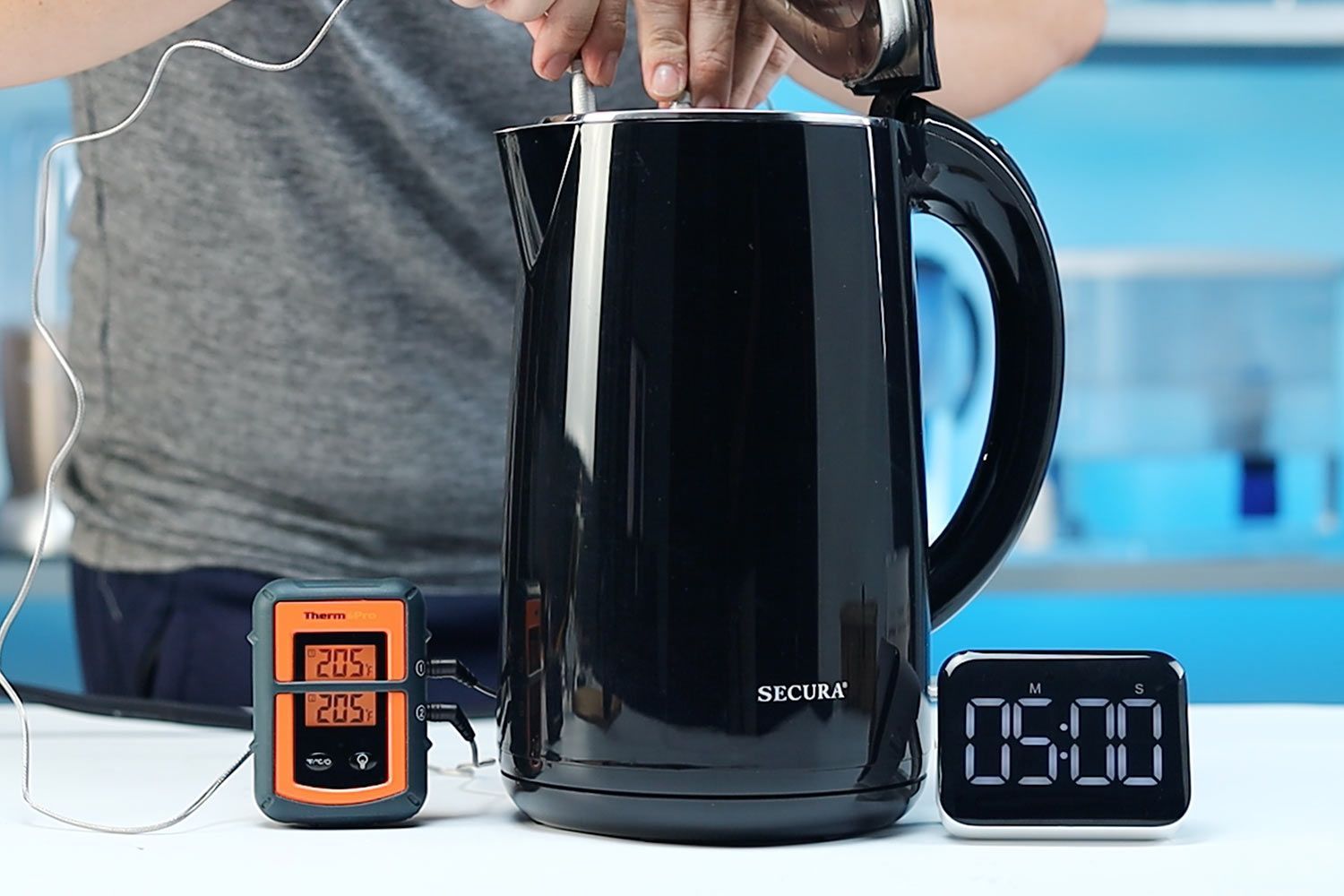 On the right is a Thermo Pro two-probe digital thermometer displaying 205°F for both probes. In the middle is the Secura Electric Stainless Steel Double-Wall Kettle (SWK-1701DA) with 1.5 liters of water and two probes inside. On the right is a digital timer displaying 5 minutes on the countdown.