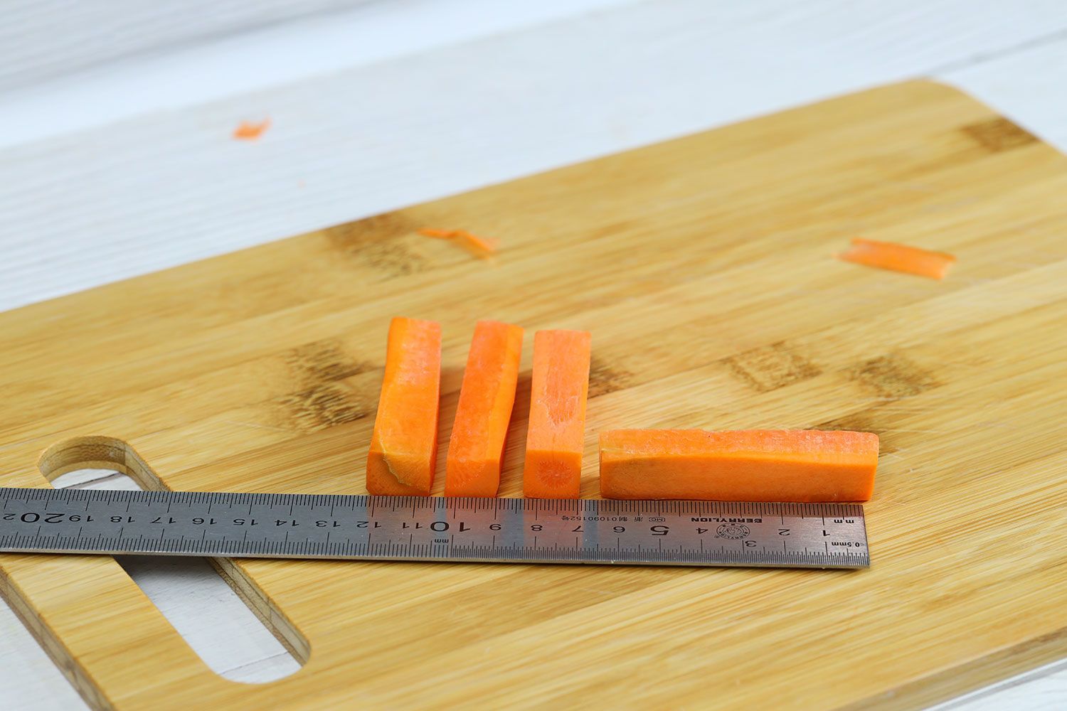 Thick carrot strips next to ruler on cutting board