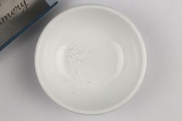 A bowl containing metal sharpening residue next to the base of the Wamery sharpener