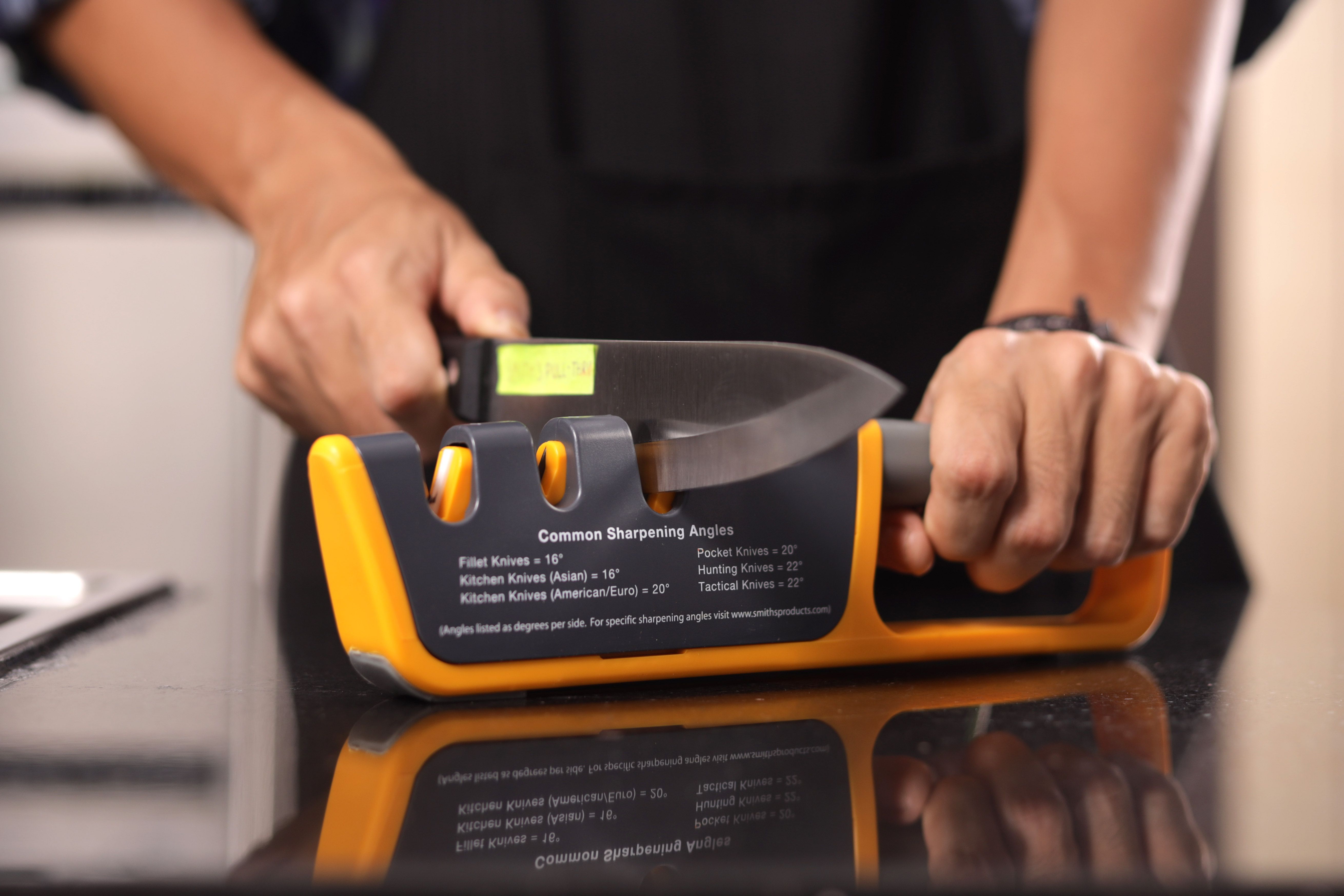 A person sharpening a knife with the Smith’s 50264 adjustable knife sharpener