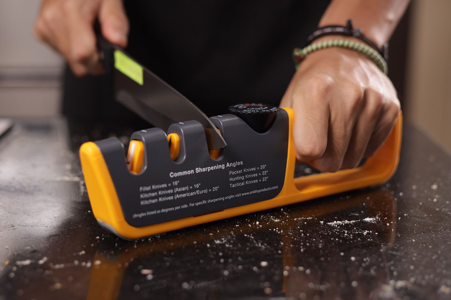 A person sharpening a knife with the Smith’s 50264 Pull-thru sharpener on a salt-sprinkled countertop