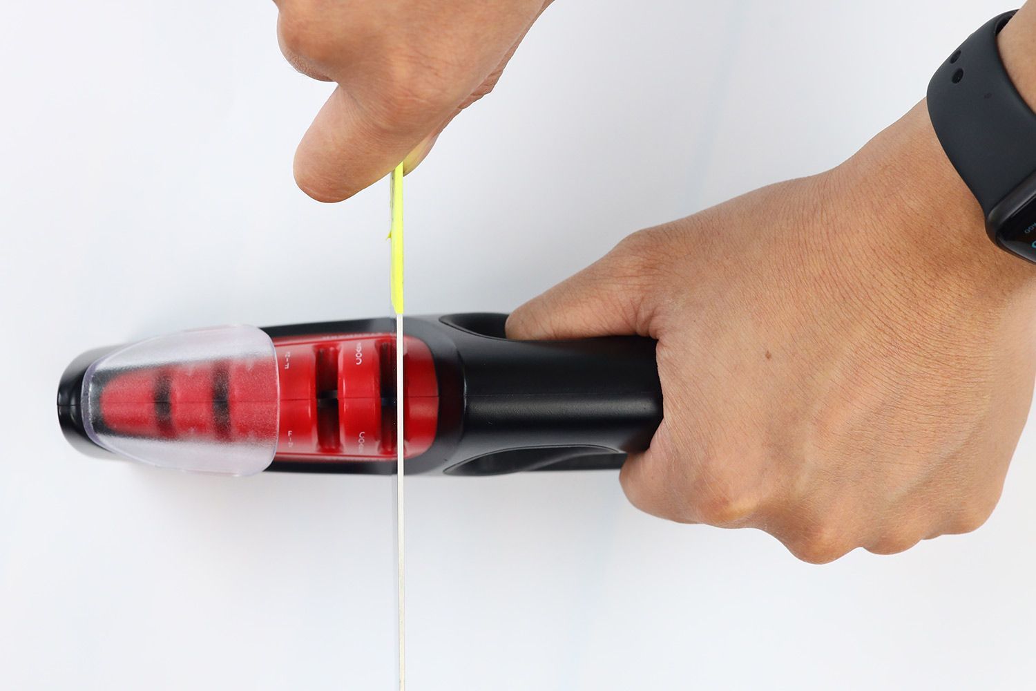 Top view of a knife being sharpened with the Zwilling pro 4 stage sharpener, the sharpener being held in one hand