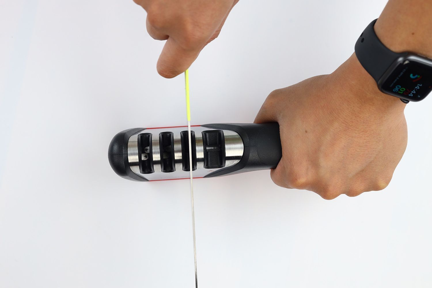 Top view of a kitchen knife being sharpened using the Longzon with 2 hands holding them