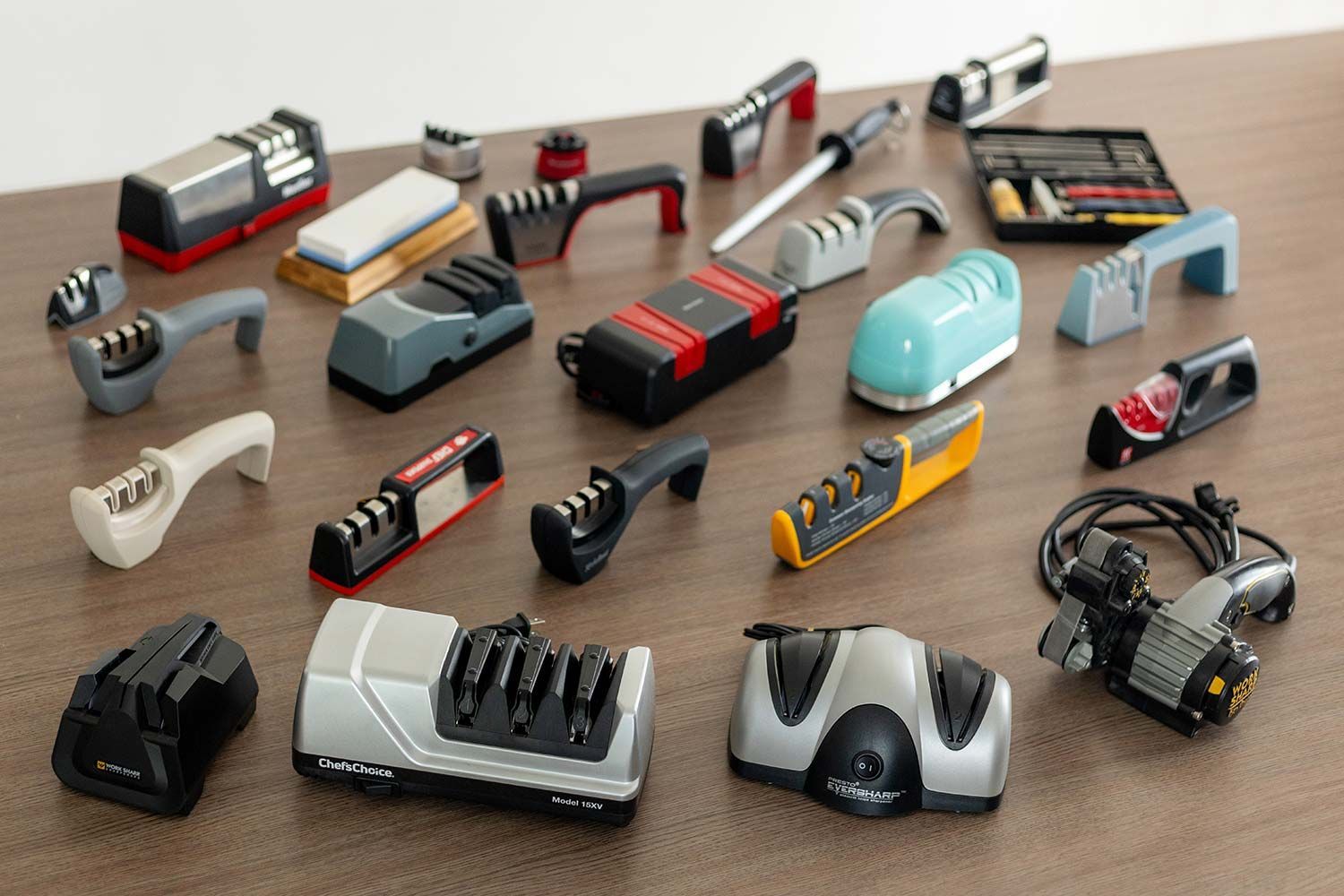 Some of the best knife sharpeners, both electric and manual, on a table, including the chef’s choice trizor VX, Work Sharp Ken Onion, Presto 08800, Kitchellence, Cubikook, Smith’s, among others