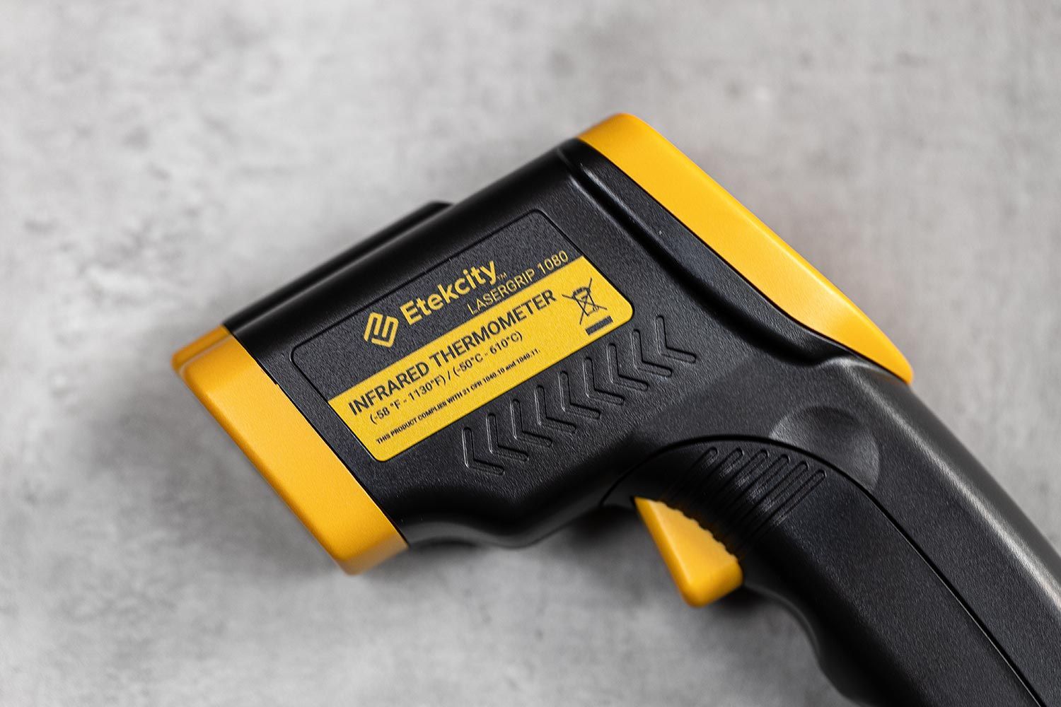 The black-and-yellow Etekcity Lasergrip 1080 on its side on a dark grey concrete table top.