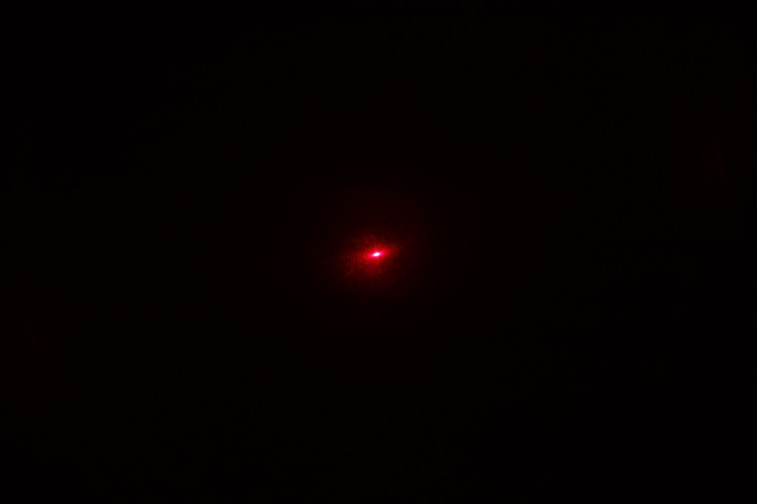 The red dot of the Eventek ET312’s laser emitter in a dark room.