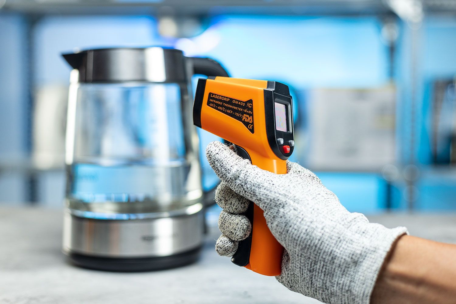 The Lasergrip GM400 Infrared Thermometer standing upright on its handle on a turn table against a blurry blue backdrop.