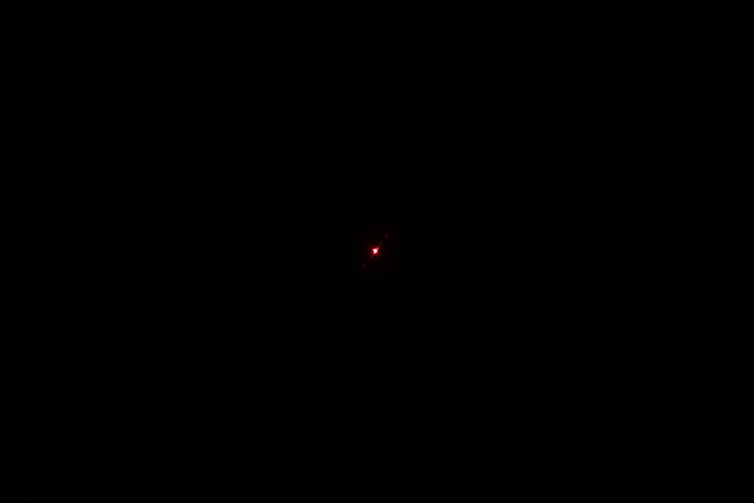 The single, red laser dot of the Lasergrip GM400 IR thermometer in a dark room.