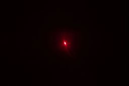 The bright red single-dot laser beam of the Sovarcate HS960D IR thermometer in a dark room.