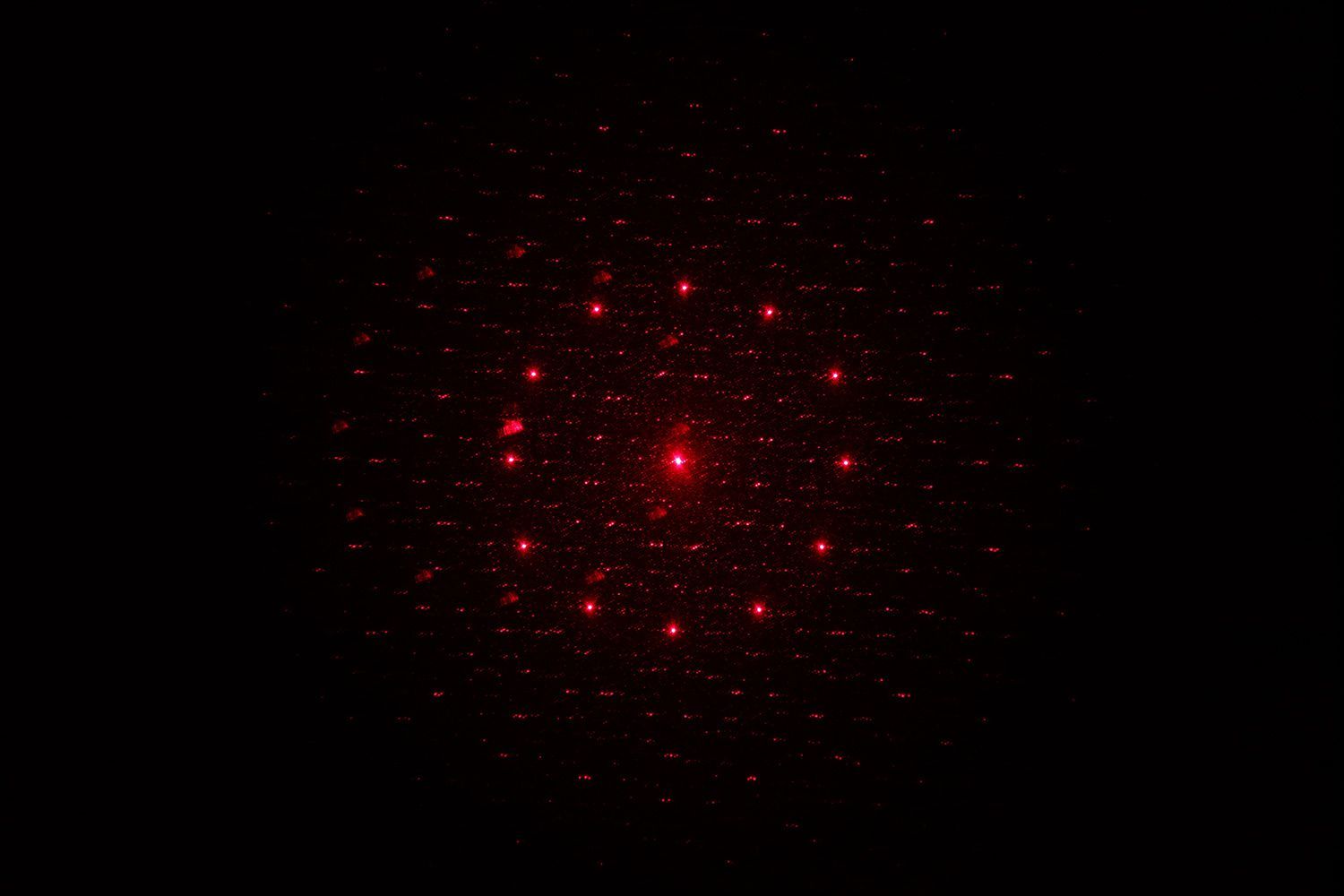 The 13-dot laser pattern of the Sovarcate HS980E on the wall of a dark room.