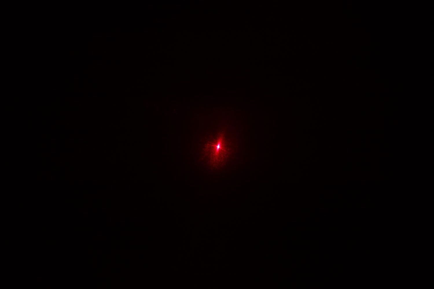 The red dot from the laser emitter of the Wintact WT530 IR thermometer in a dark room.