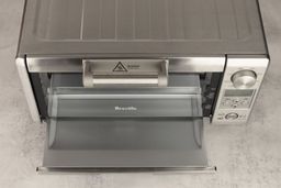 View from the top onto a slide-out crumb tray of the Breville BOV450XL Mini Smart Toaster Oven on a grey background.