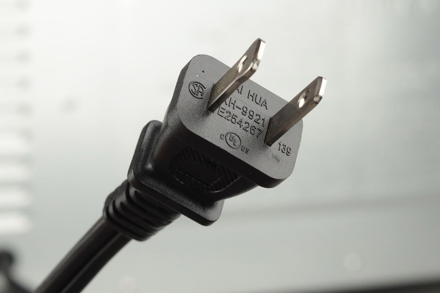 A two-pronged plug power cord. In the background is the stainless steel Cuisinart TOB-40N Custom Classic Toaster Oven.