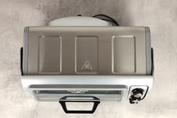 The top of the stainless steel Hamilton Beach 31127D 6-Slice Easy Reach Roll Top Door Toaster Oven on a grey background.