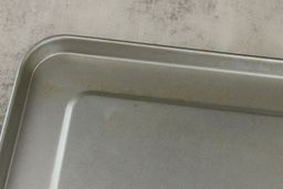 The cleaned silver baking pan of the Hamilton Beach 31127D 6-Slice Easy Reach Roll Top Toaster Oven with some discoloration.