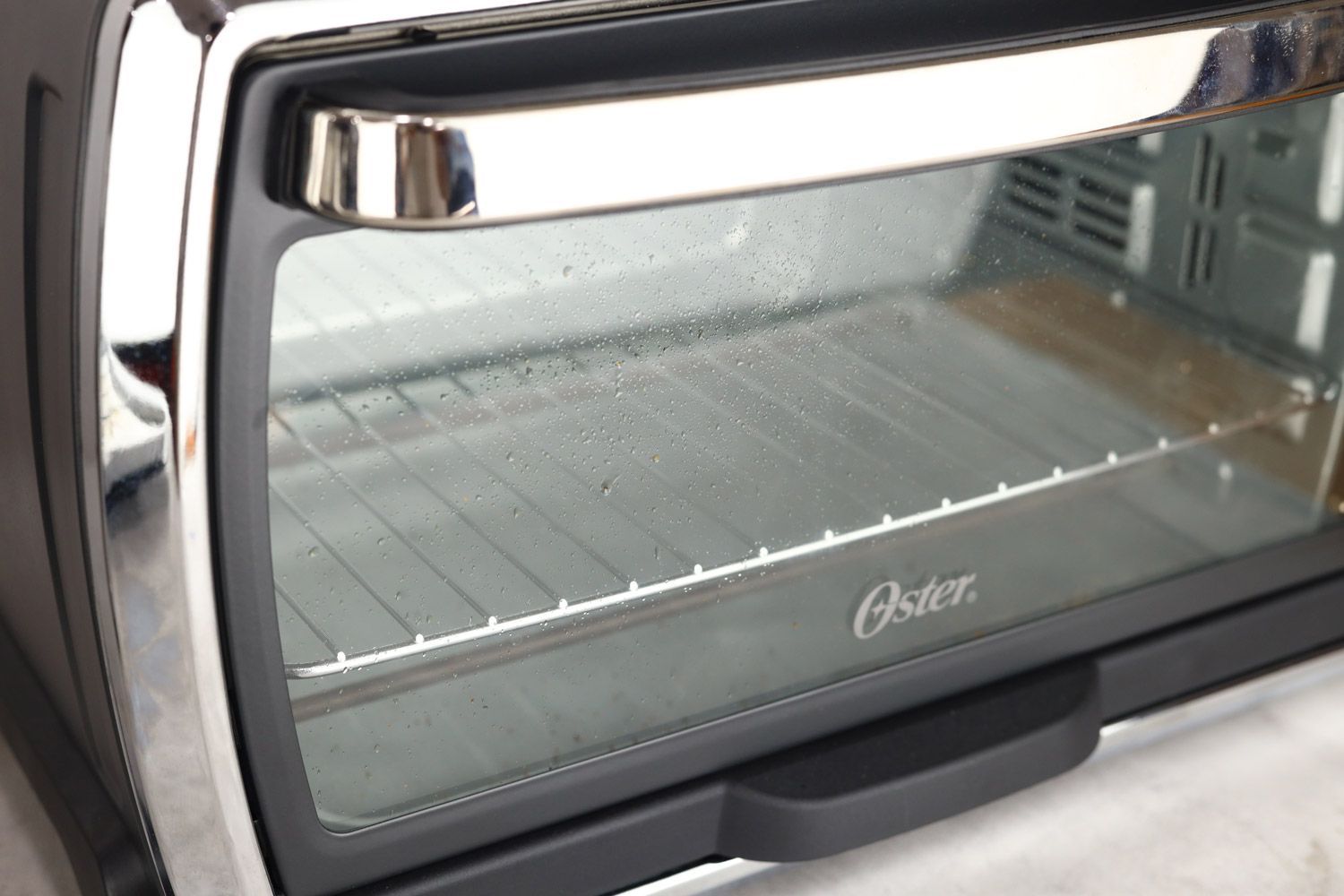 Grease on the glass door of a closed stainless steel Oster TSSTTVMNDG-SHP-2 6-Slice Large Digital Convection Toaster Oven.