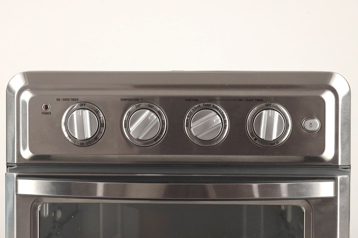 From left to right, the control panel of the stainless steel Cuisinart TOA-60 Convection Toaster Oven Air Fryer has four control dials for on/oven timer, temperature, function, on/toast timer, and a light toggle.