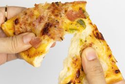 Two hands break apart a slice of pizza with melty cheese, meat, and green bell peppers on top baked using a toaster oven.