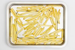 Pieces of baked french fries using a toaster oven on a silver baking pan on a white background.