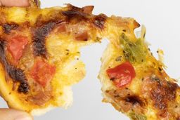 Two hands break apart a slice of pizza with melty cheese, meat, and green bell peppers on top baked using a toaster oven.