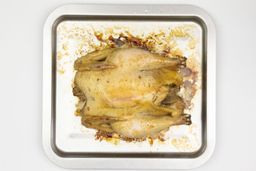 A whole roasted chicken using the Cuisinart TOB-40N Custom Classic Toaster Oven on a silver baking pan on a white background.