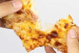 Two hands break apart a slice of pizza with melty cheese, meat, and green bell peppers on top baked using a toaster oven.