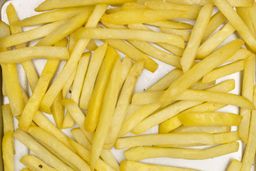 A close-up of pieces of baked french fries using the Hamilton Beach 31401 Oven on a silver baking pan on a white background.